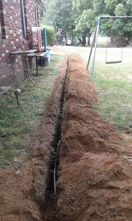 Freshly excavated sewer line trench across a Mesquite backyard